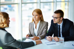 Two serious business partners listening attentively to young mans job interview questions